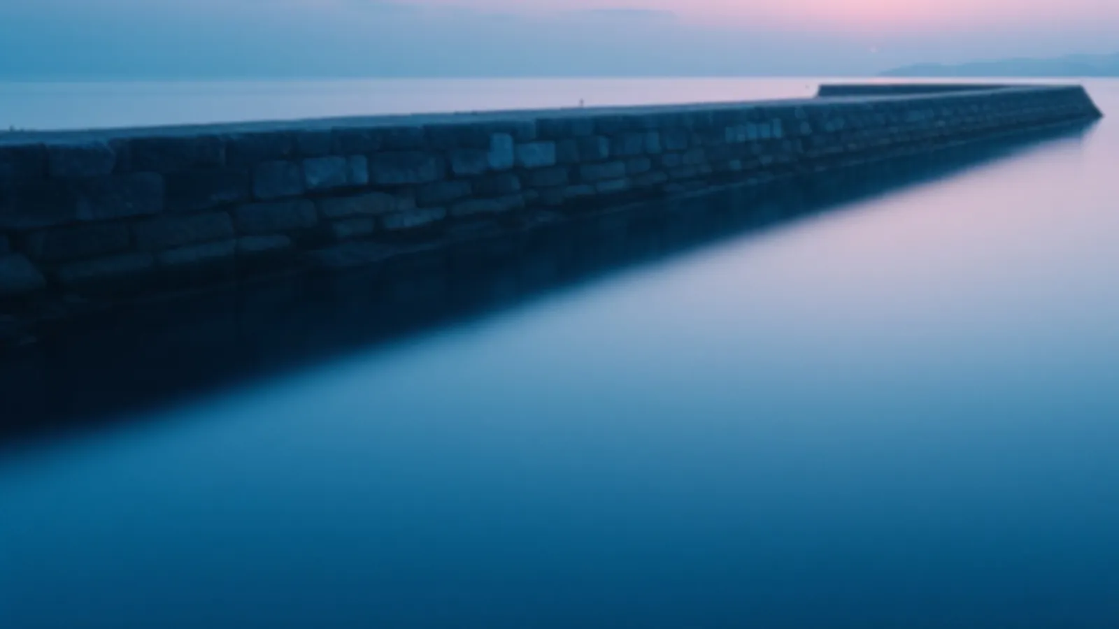 Calm harbour water beside a stone breakwater in soft dawn light, the BallastWorth view of online loans for emergencies, $100 – $5,000